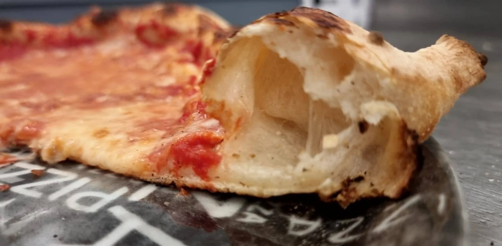 Dettaglio del cornicione di una pizza appena sfornata